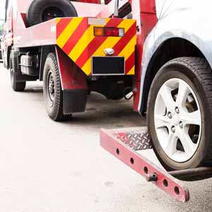 An extensible steel wheel-lift towing yok, on a light duty tow truck, is fitted under the front wheels of a disabled vehicle so it can be towed away.
