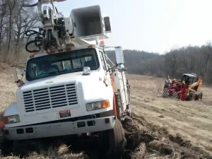 This small bulldozer pulling a utility truck out of a rut in a field is a great example of what off-road recovery is.