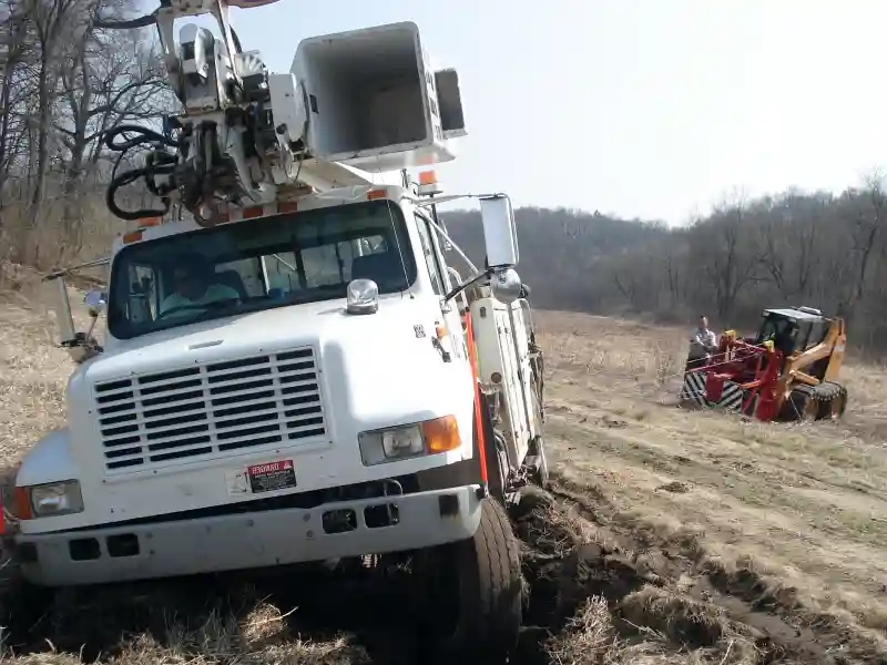 This small bulldozer pulling a utility truck out of a rut in a field is a great example of what off-road recovery is.